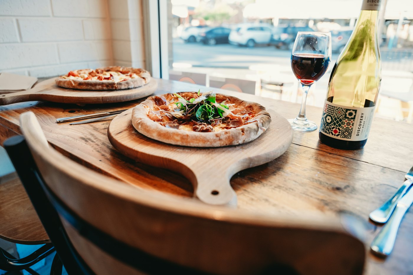 Pizza servida na mesa ao lado de uma taça de vinho